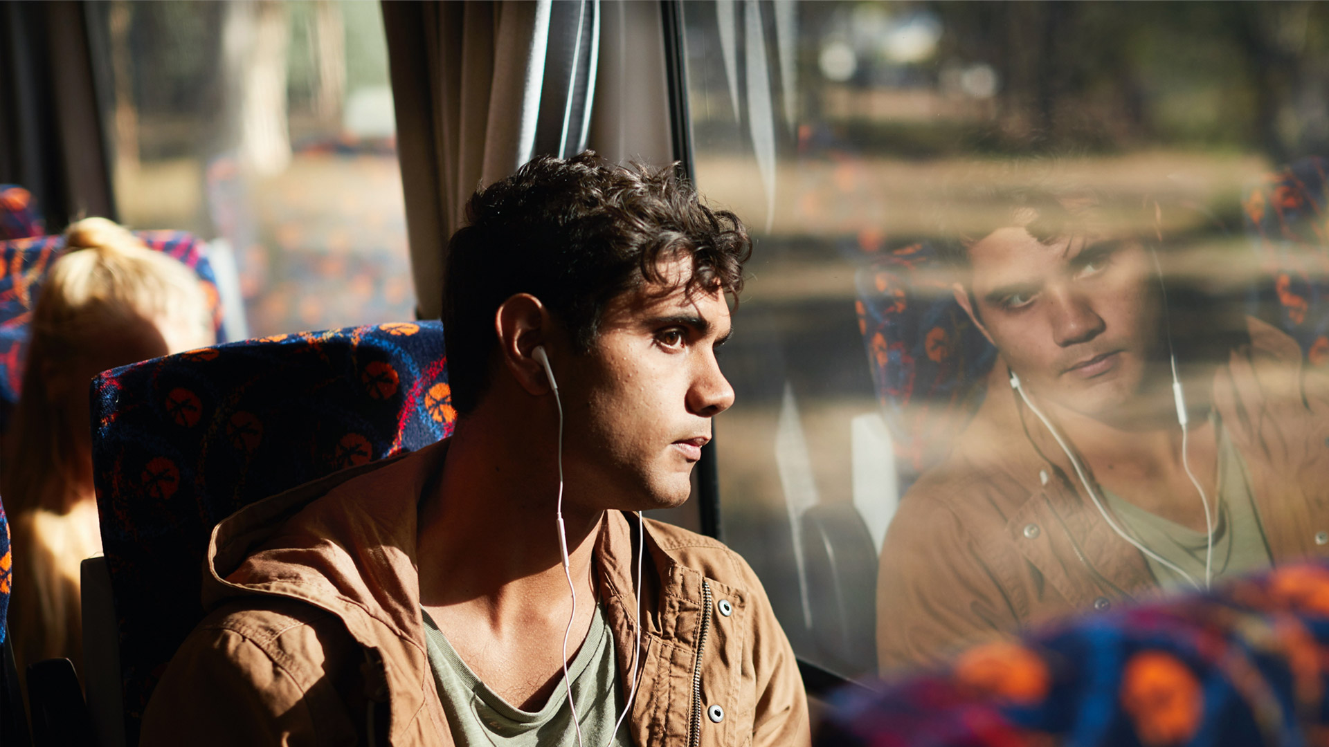 Man wearing headphones looking out coach window